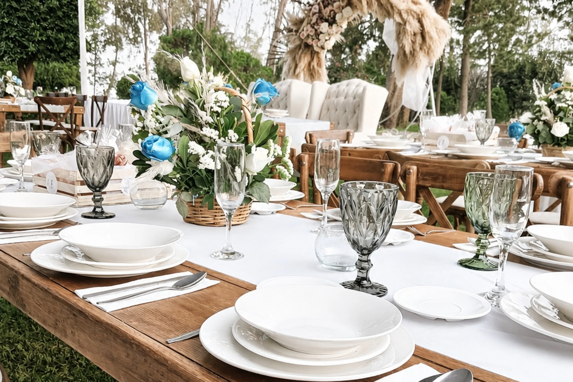 Mesa de madera con vajilla blanca, copas y flores