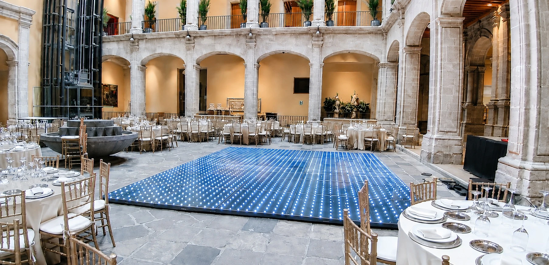 Patio con arcos de cantera, mesas redondas y pista de baile iluminada